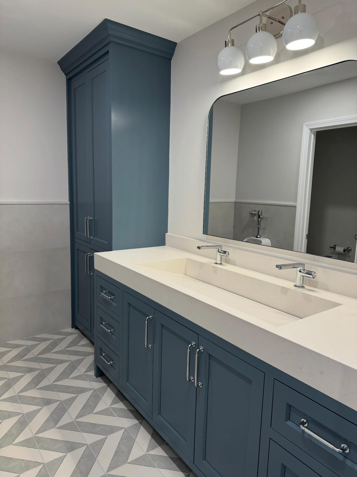 Clean bathroom with navy vanity and polished mirrors